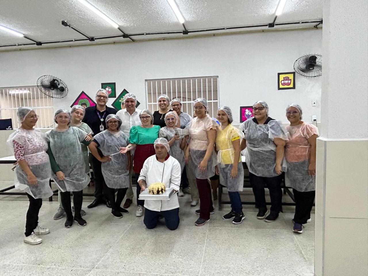 pessoas em pé com touca no cabelo segurando um bolo